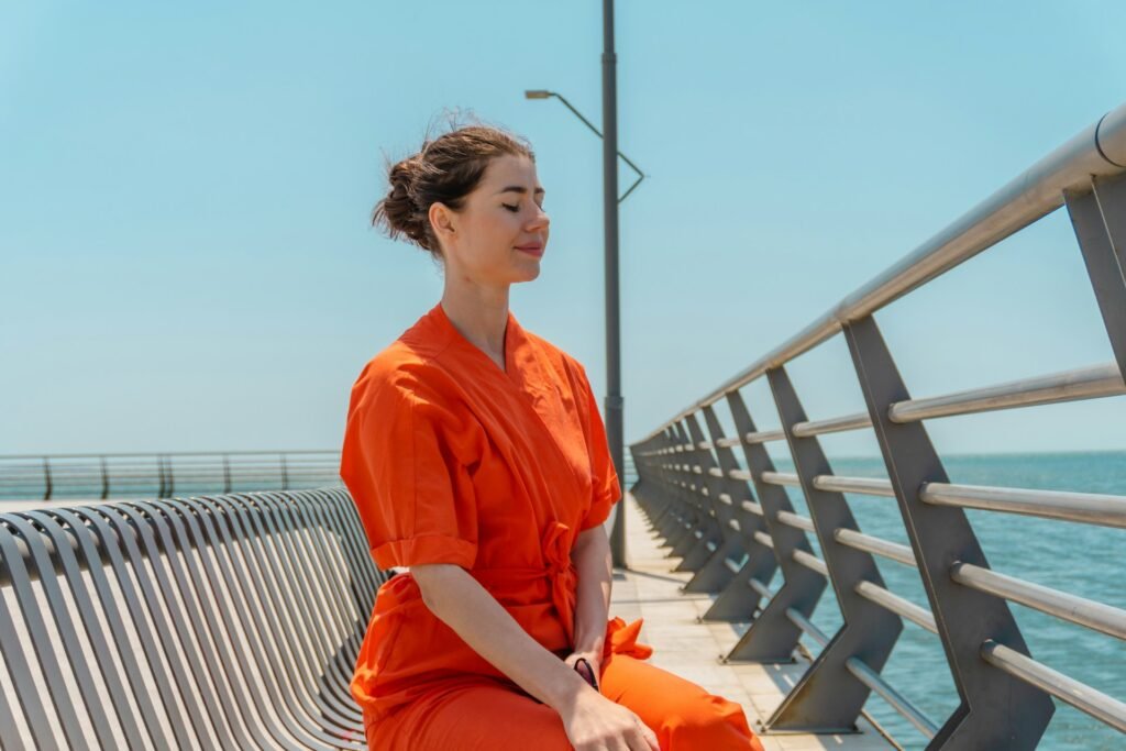 Woman in orange dress meditating by the ocean
